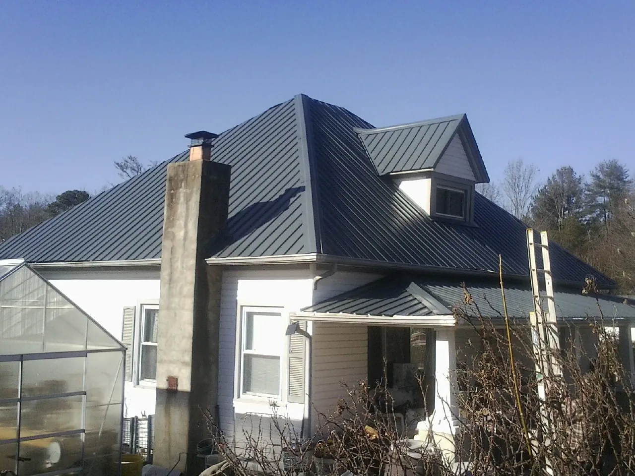 Dark blue standing seam metal roof on a white farmhouse with dormer — Slate & Tile Roof Repair by Roofing Brothers in Ilwaco