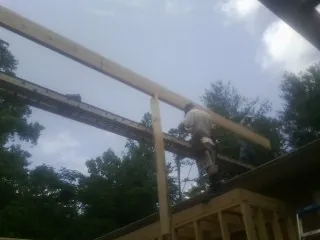 Carpenter setting a ridge beam over a new addition frame — Ice Dam Removal by Roofing Brothers in Ilwaco