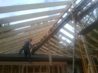 Rafters going up over a new addition with a worker on the wall in Ilwaco