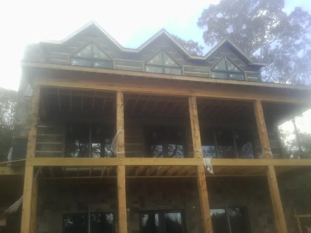 Dormers and porch framing on a large log home under construction — Roof Coating work by our crew in Ilwaco