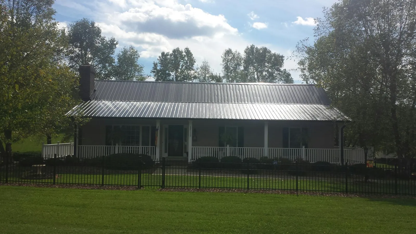 Gray metal roof on a brick ranch with a full width front porch — Gutter Guard Installation work by our crew in Ilwaco