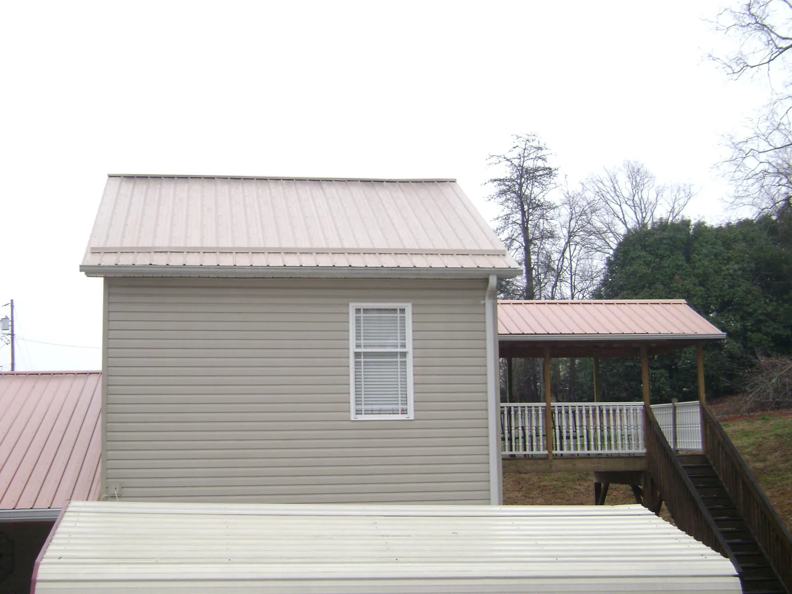 Tan metal roofs on a two story addition and attached porch, from a Roof Replacement job in Ilwaco