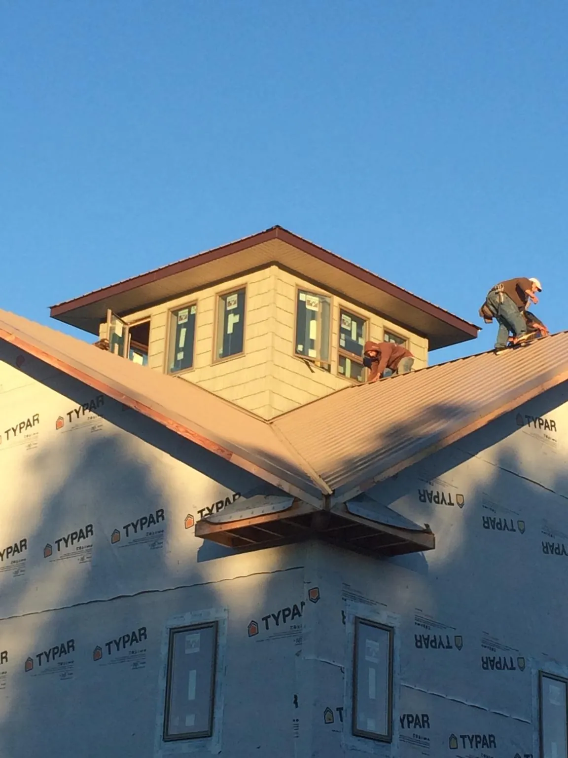 Roofers working around a rooftop cupola on a new metal roof at sunset — Roof Waterproofing in Ilwaco by Roofing Brothers